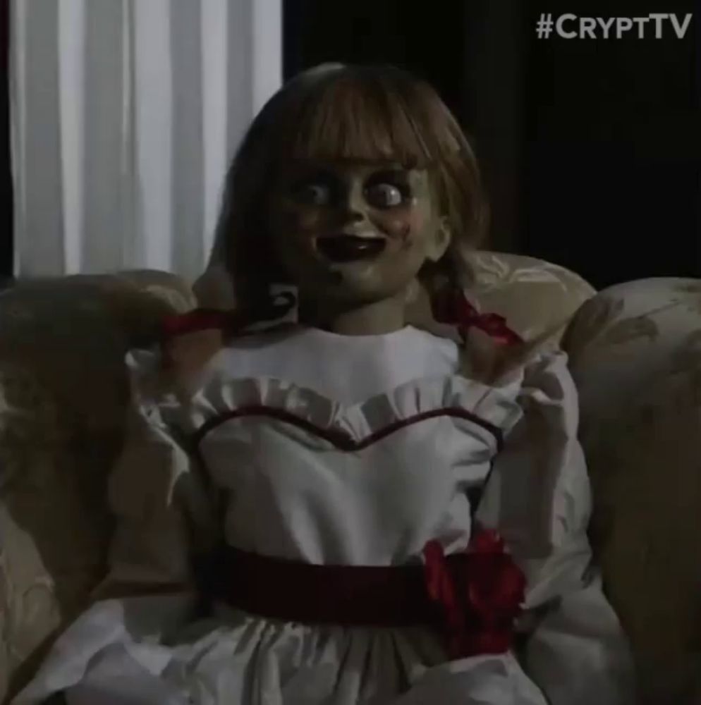 a creepy doll is sitting on a couch with the words #crypttv behind it