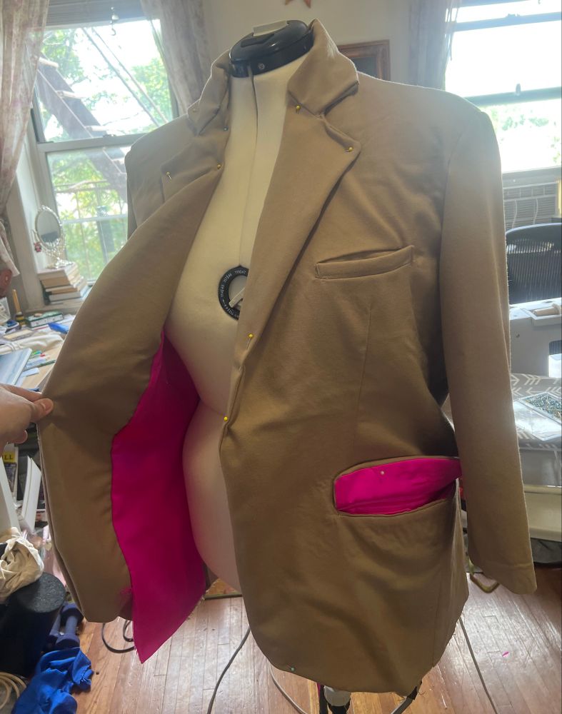 A camel blazer opened to show its fuchsia lining 