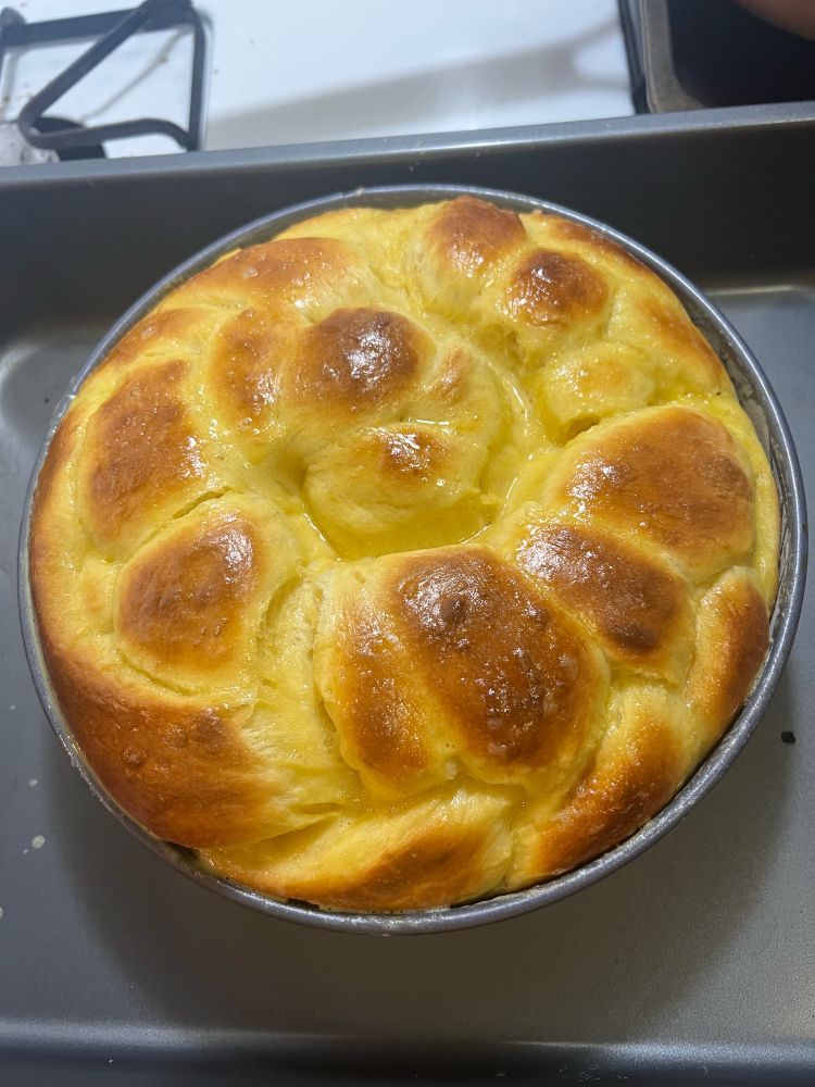 Braided brioche bread halfway thru baking (second egg wash time) that is looking golden like a sunflower