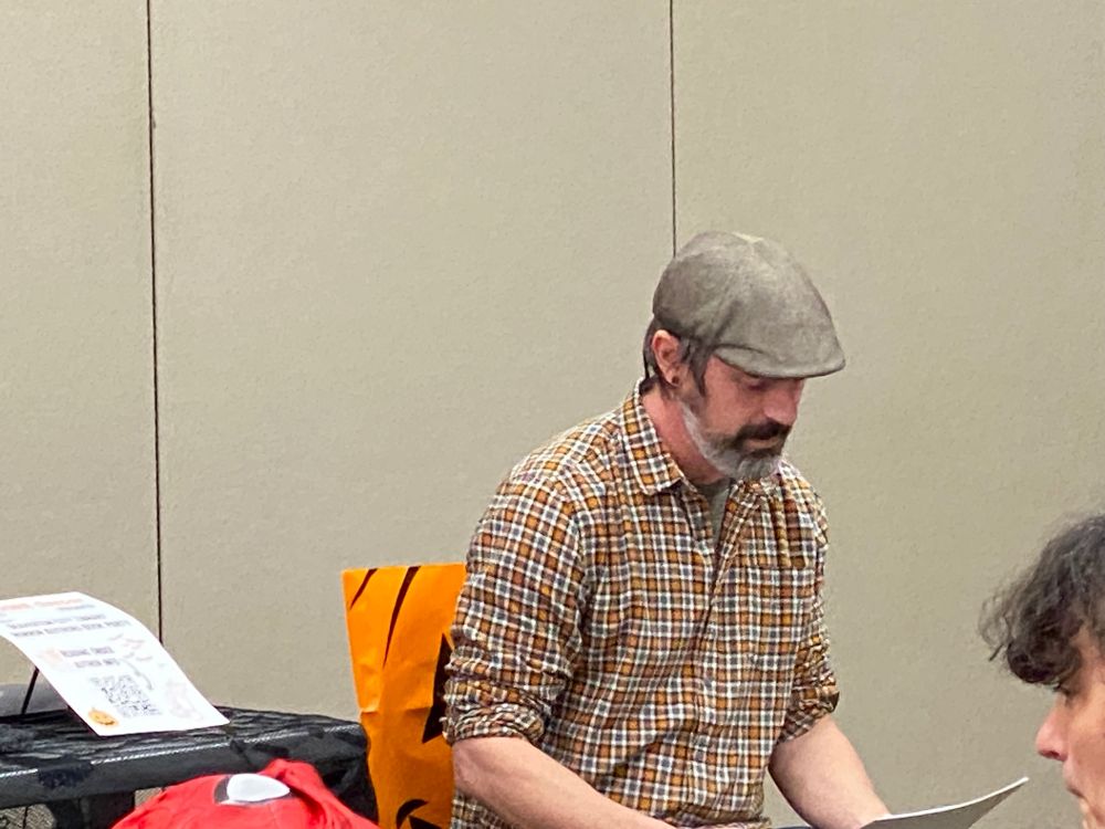 Dan Finnegan reads a story from sheets of paper in front of an audience at the Horror Authors Book Party at Beaverton City Library on Saturday, October 25, 2025.