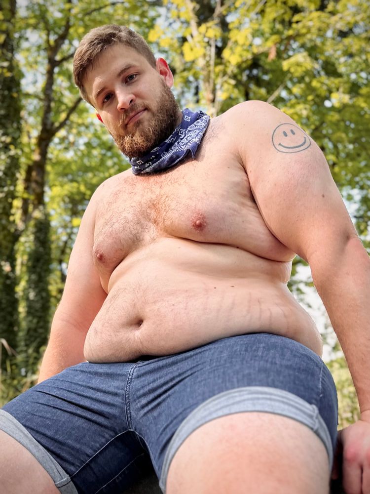 sitting on a park bench with my belly and fat rolls out while wearing jean shorts and a bandana