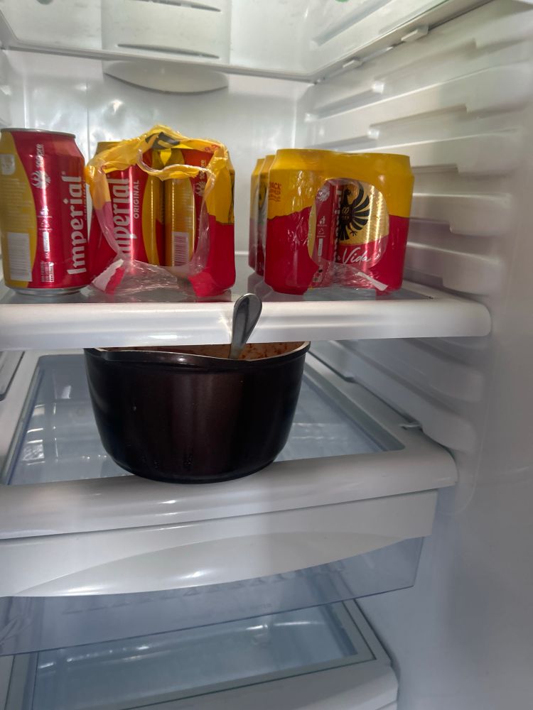 Picture of fridge with only imperial beer and a black pot uncovered with a fork still in it inside 