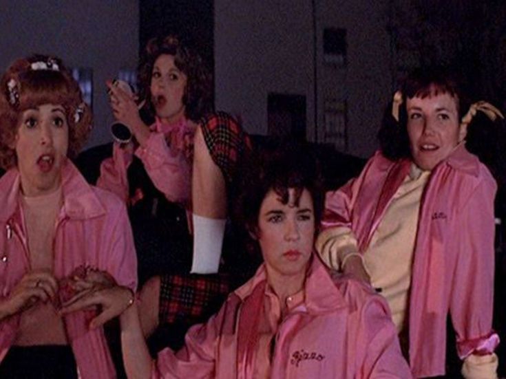 The 4 Pink Ladies from Greese, the one on the left with red hair has her mouth open in shock, the one beside her is putting lipstick on, the one on the right is looking at something in interest, and the one front and center is glaring at the same thing. 