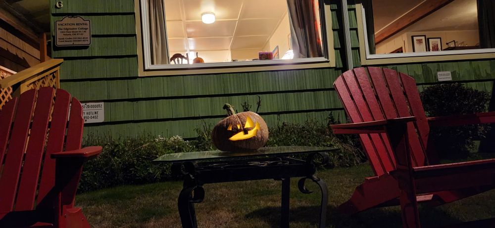 Carved and lit pumpkins from our garden at home sitting on a table in front of our vacation rental beach cottage