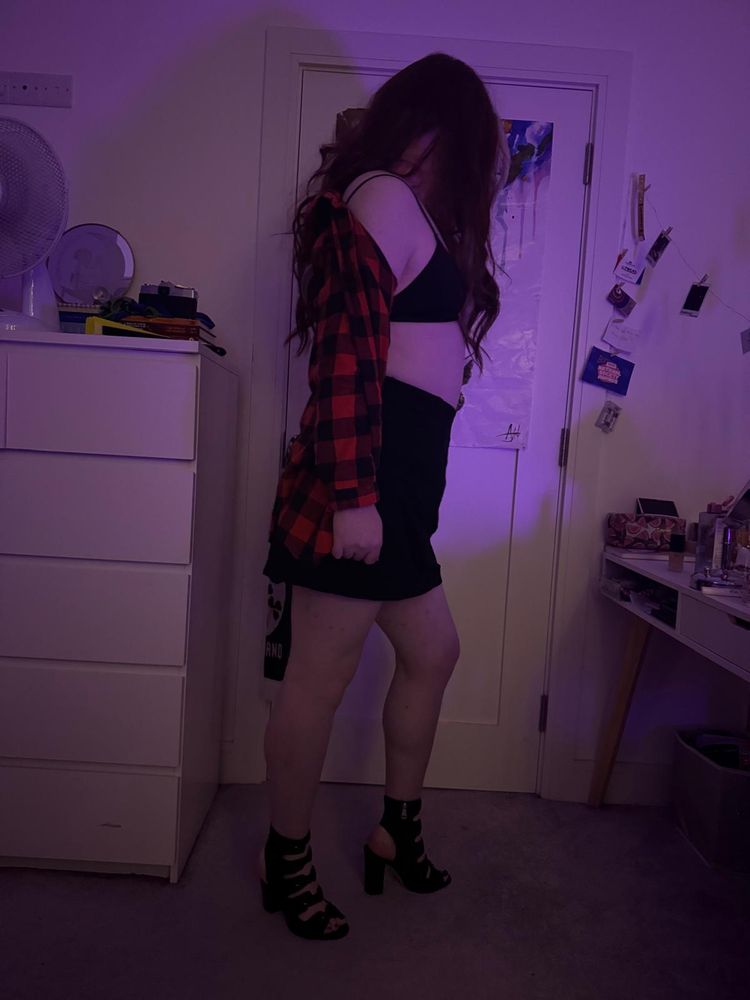 roxie standing in side profile in heels, a miniskirt and a bra, red flannel shirt hanging off its shoulder.