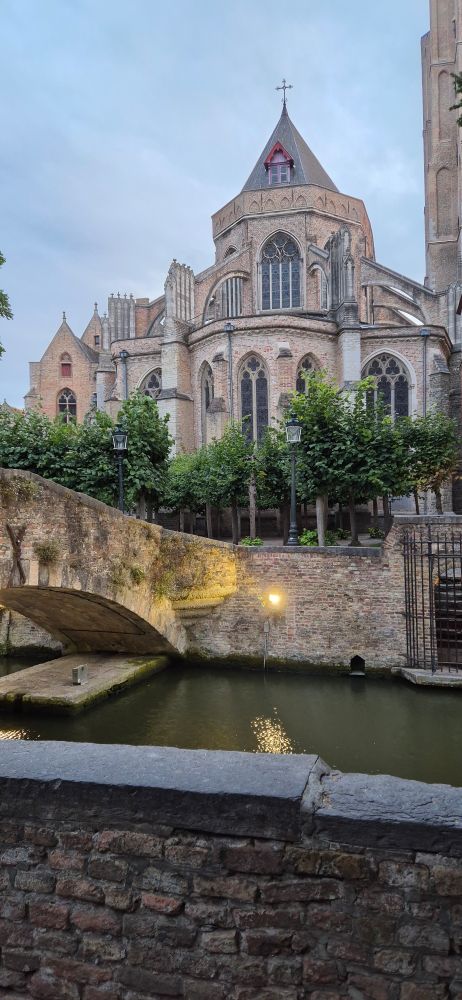 A picture of a stone church next to a stone bridge crossing a canal in Bruges
