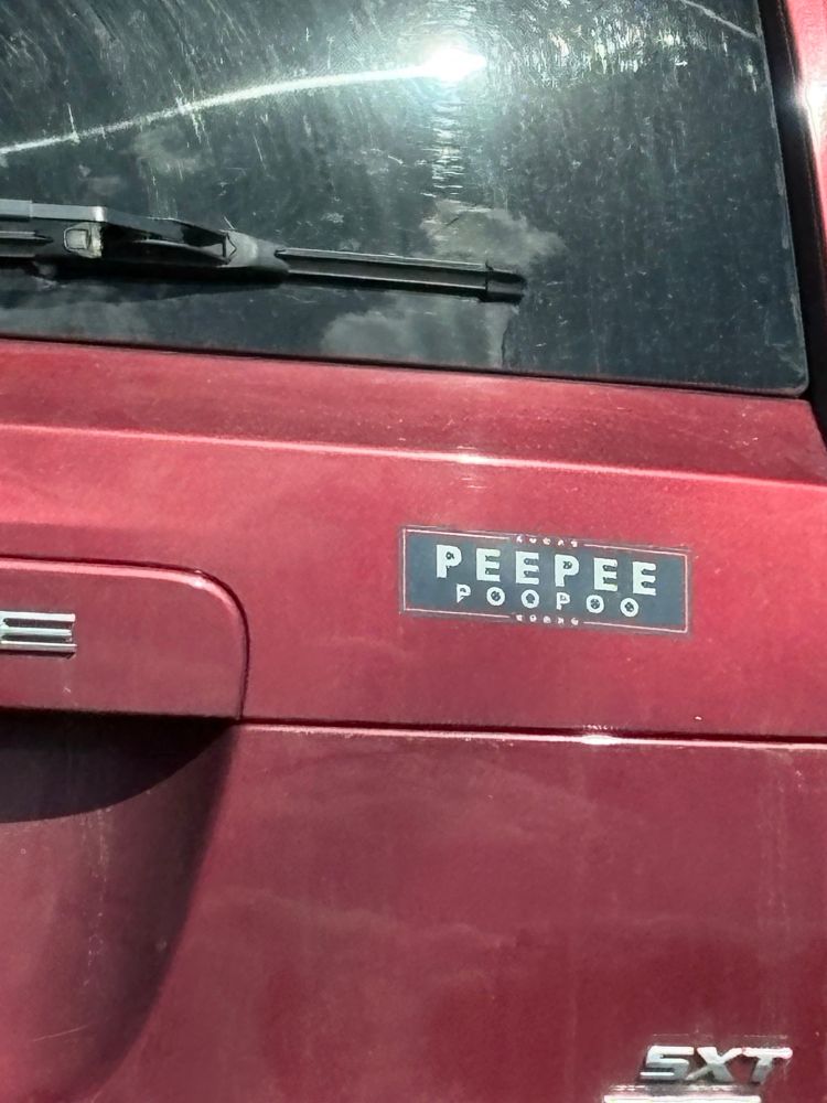 A bumper sticker on the back of a red suv. The sticker is in the manner of president/vice president where the top says PEEPEE & the VP says POOPOO