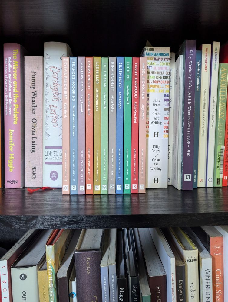 A bookshelf showing the colourful spines of the Modern Women Artists series between lots of other books 