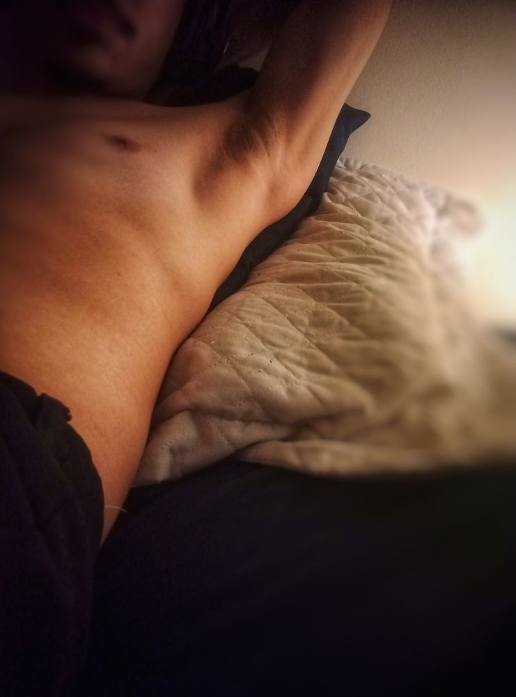 Foto de um homem sem camisa mostrando seu suvaco para a câmera.

O cenário é iluminado por uma luz lateral com a foto acontecendo em uma cama 

Ele está deitado em alguns travesseiros para deixar seu corpo inclinado 