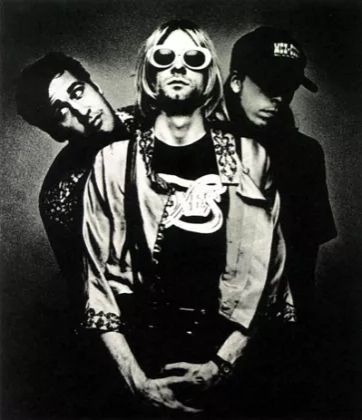 Foto em preto e branco da banda "Nirvana", mostrando três integrantes. Da esquerda para a direita: Krist Novoselic, Kut Cobain e Dave Grohl.