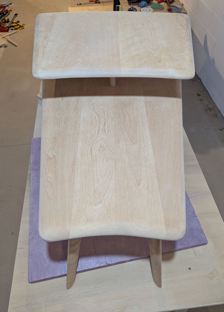 A mostly top down view of a mid century end table, sanded down to the bare wood.