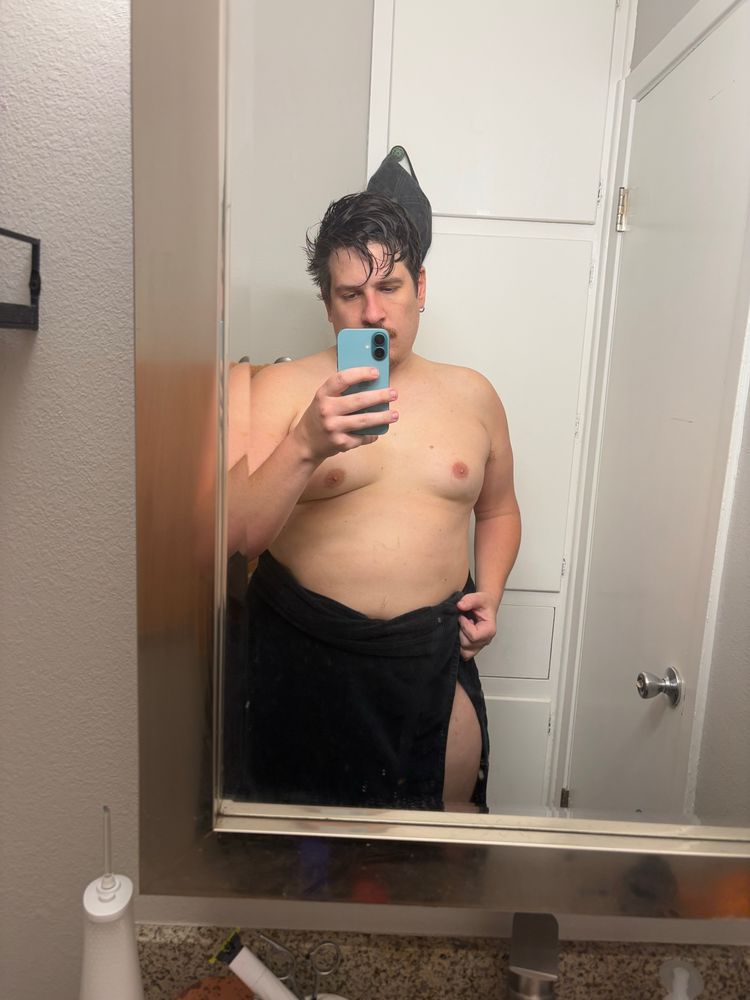 Man standing in front of a mirror in a black towel 