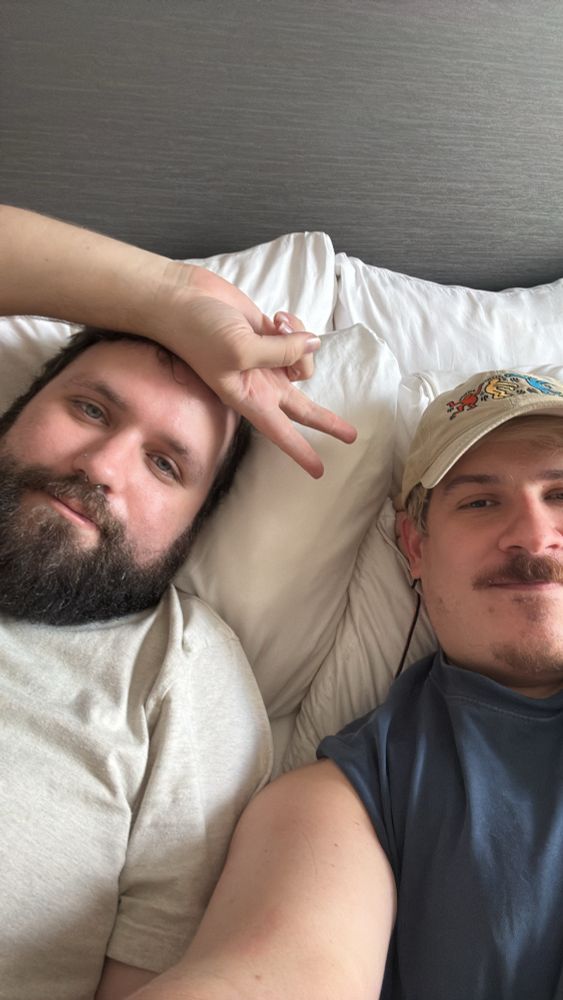 Two men laying on a bed 