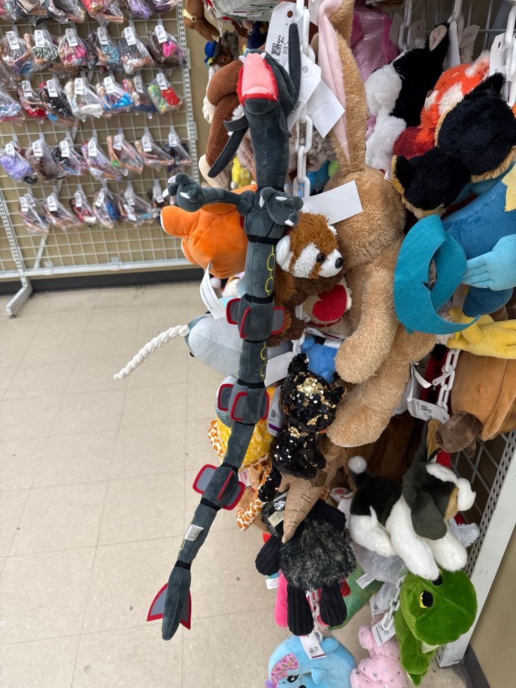 picture of a rack of plushes with a shiny rayquaza plush on it 