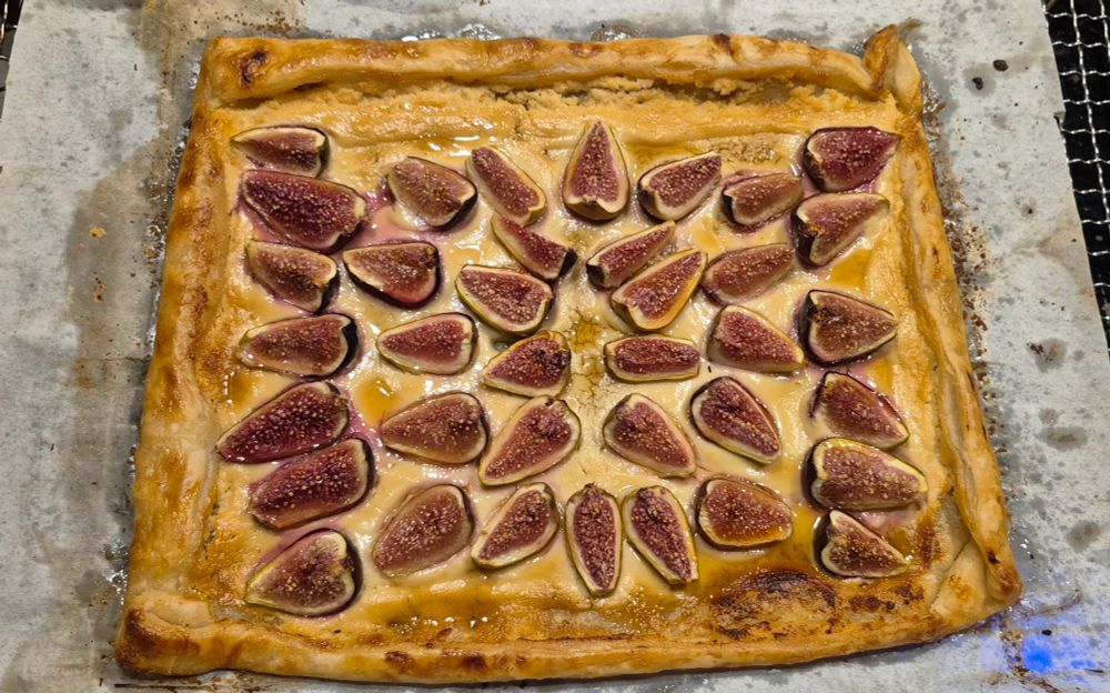 A top-down picture of a freshly baked galette. It has goat cheese filling that is topped with fig quarters and a drizzle of honey.