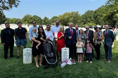 Trump smiling with a thumbs up at gravesite with family.