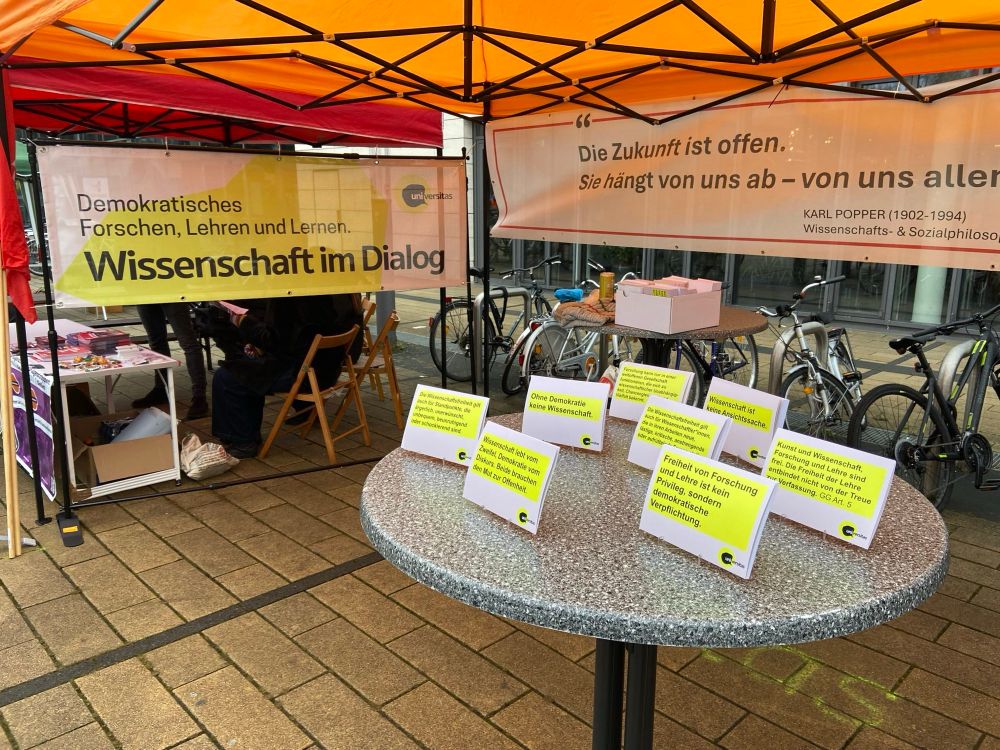 Stand der universitas Hochschulgruppe mit Postkarten und Popper-Plakat: “Die Zukunft ist offen. Sie hängt von uns ab - von uns allen”