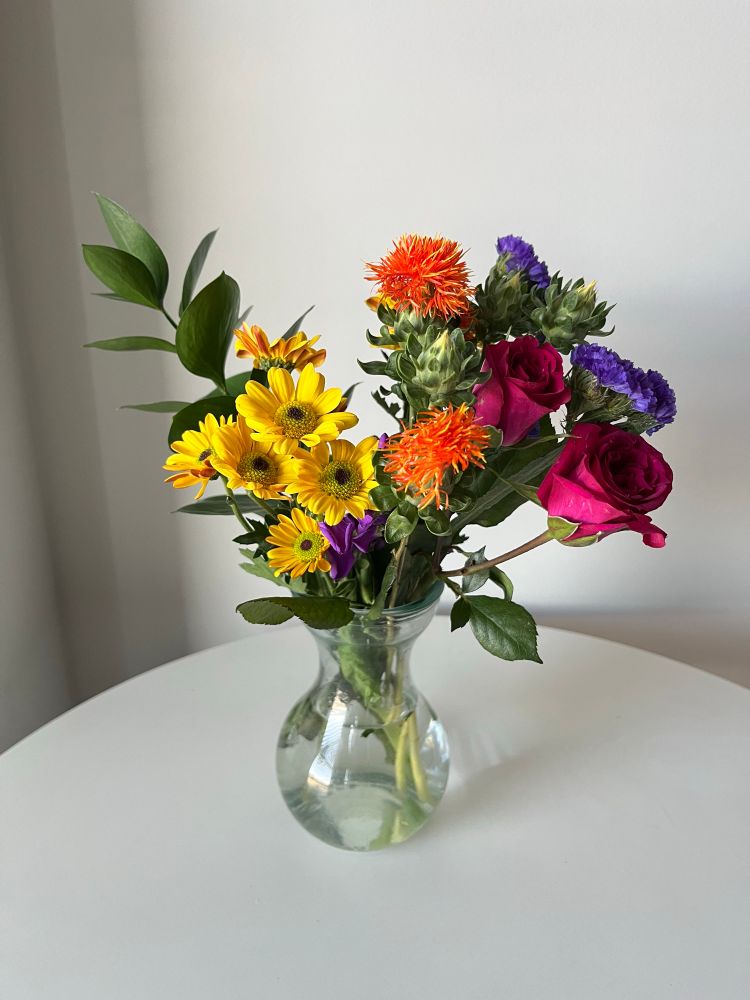 A bouquet of colorful flowers in a vase on a table. 