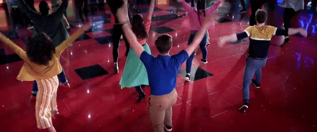 a group of people are dancing in a circle with their arms outstretched