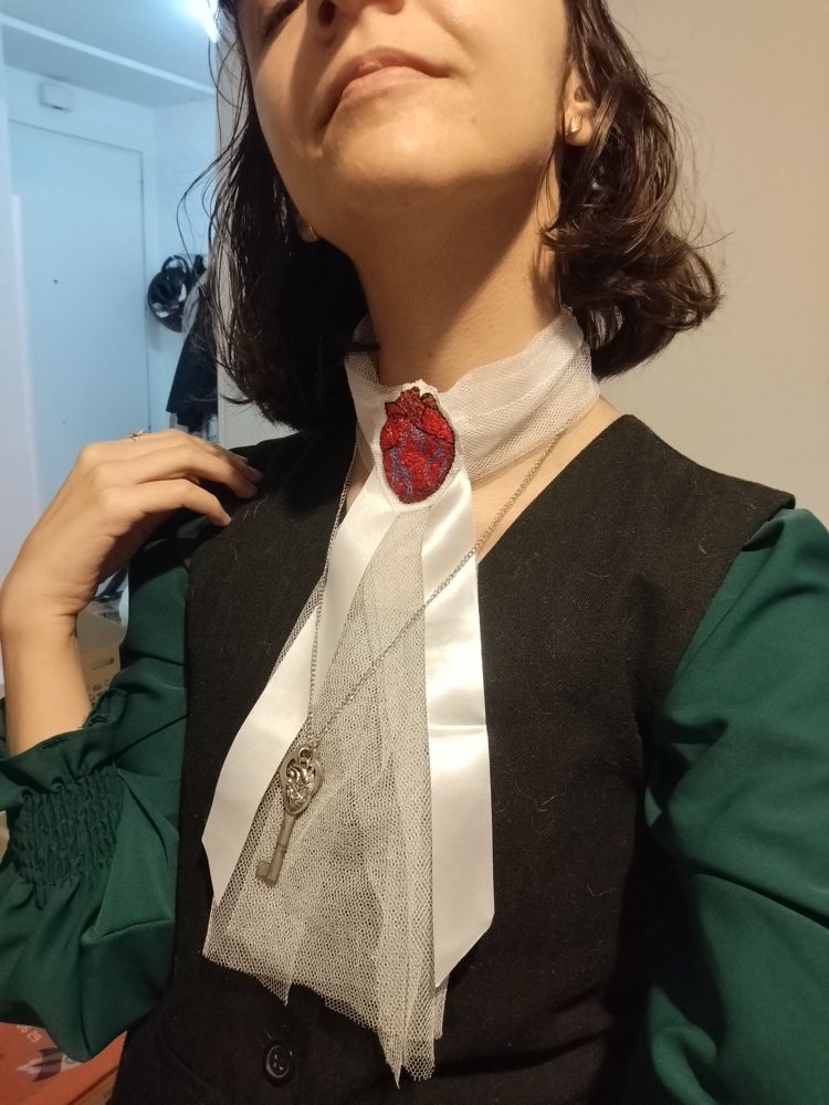 Es el cuello con gasa blanca y una cinta y el bordado de corazón anatómico 
