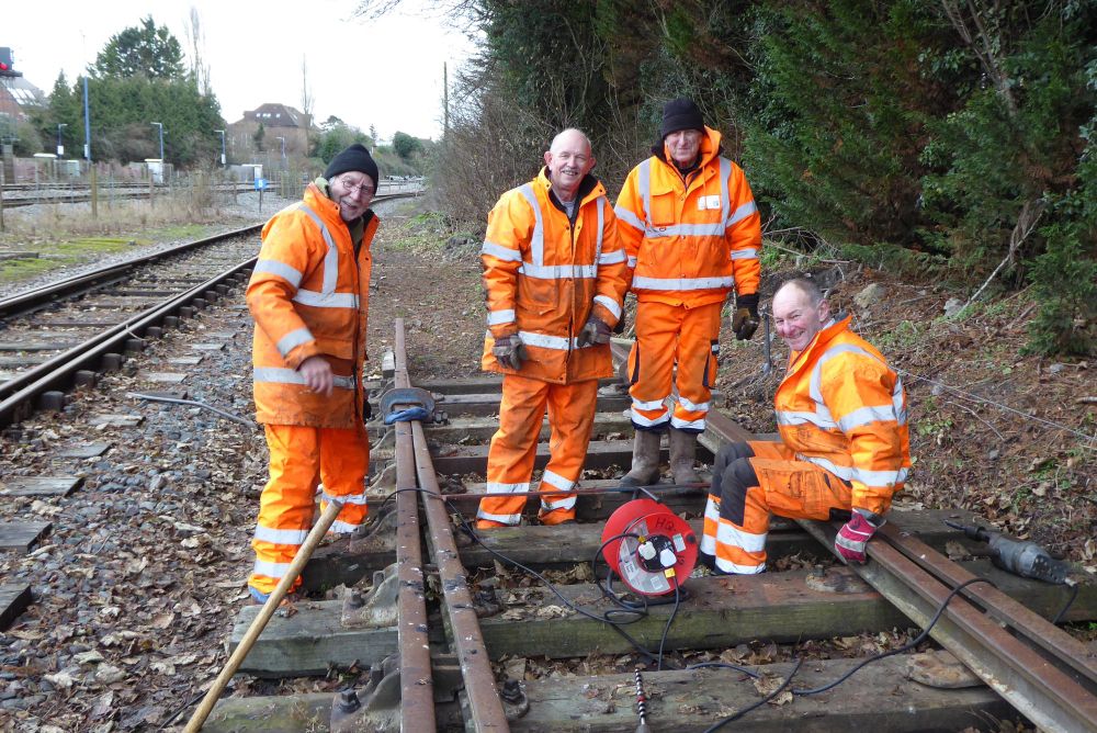 Four volunteers in Orange HV PPE are shown maintaining a set of points that will be used in the Independent Line construction work.
