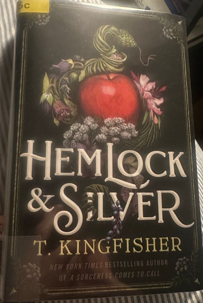 The cover of Hemlock & Silver, by T. Kingfisher, with a still life of an Apple surrounded by plants and a snake.