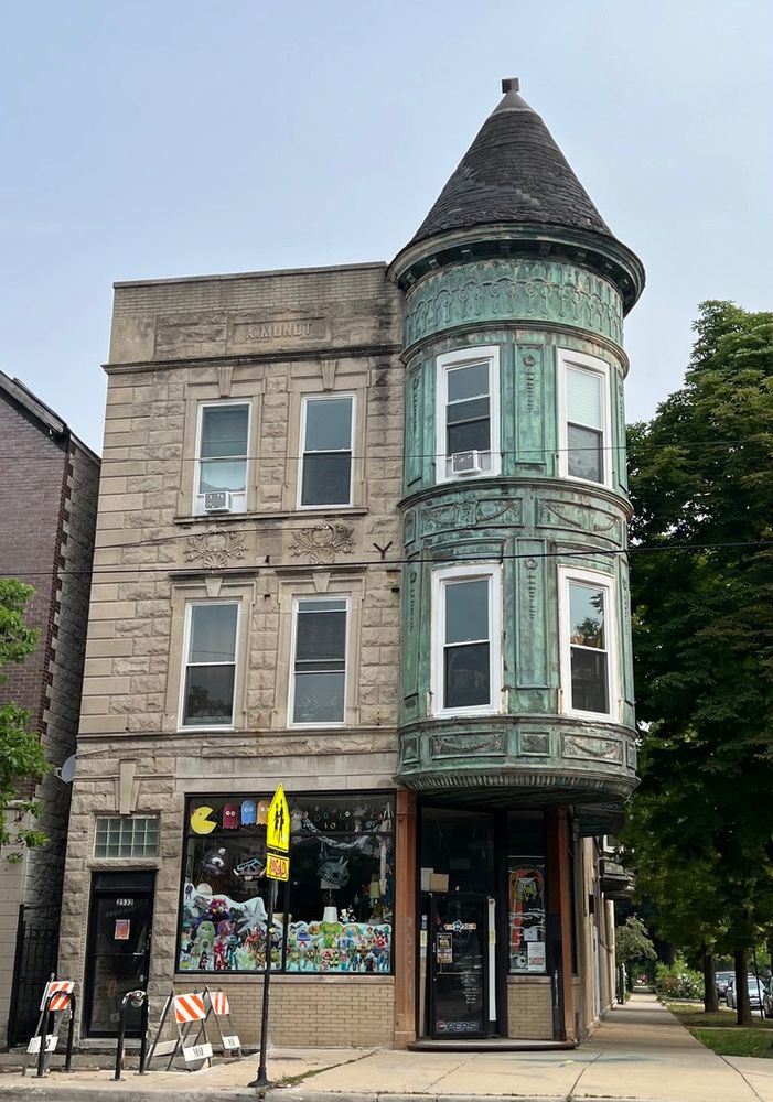 A building located on a street corner.  It appears to be of pressed metal and cast stone.