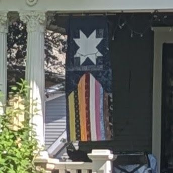 Homemade Minnesota Pride flag hangs vertically from a porch in Saint Paul, MN