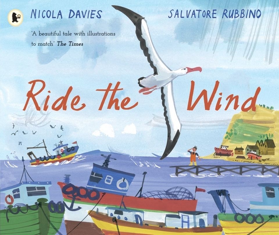 Jacket image, Ride the Wind by Nicola Davies, illustrated by Salvatore Running. . An albatross flies across the image, against the backdrop of fishing village and boats at anchor. One fishing boat in the distance is attracting a flock of gulls. 