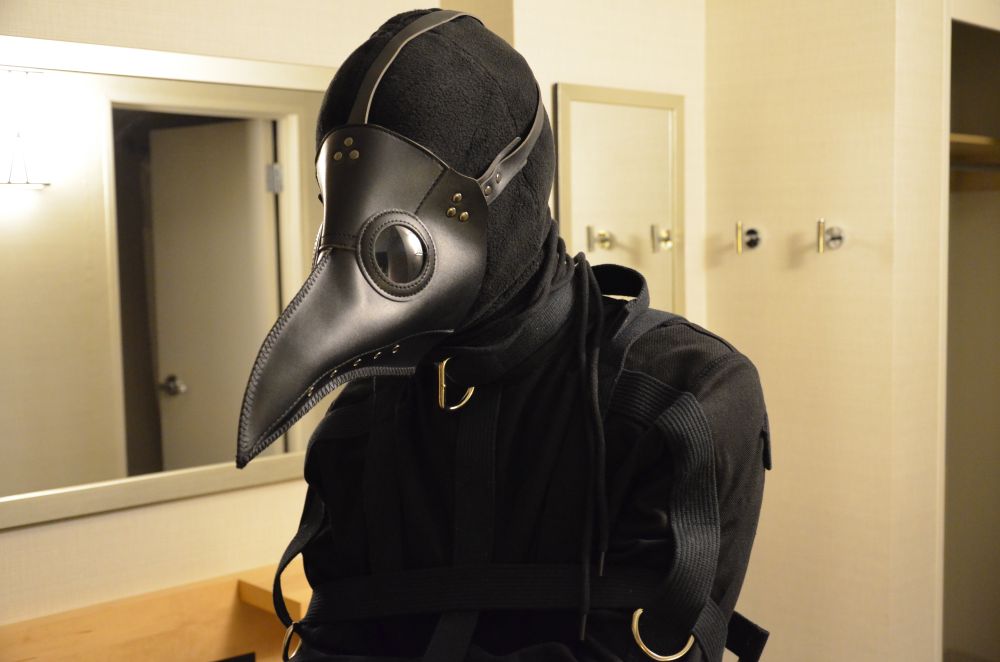 Pic of patient zero (me) seemingly nodding. Wears a straightjack with a laced hood accompanied by a plague doc mask