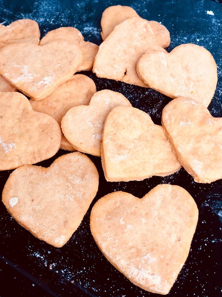 A batch of heart-shaped crackers, slightly red from tomato