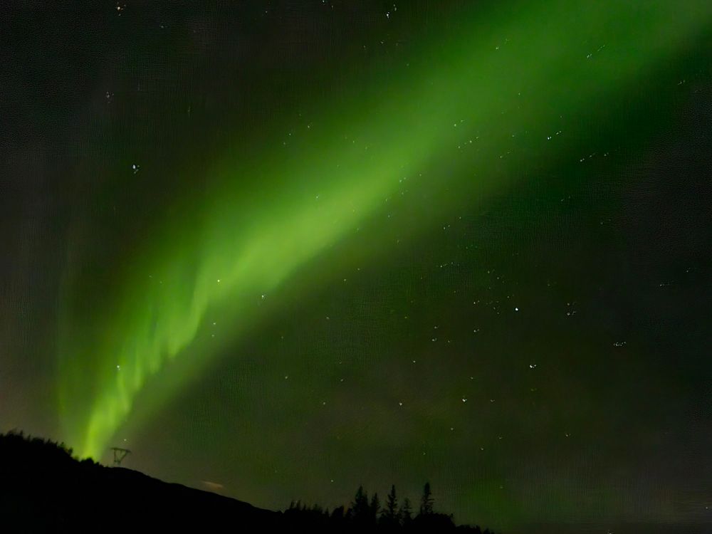 a green streak of aurora across the night sky