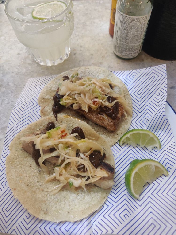 Two soft shell tacos and two lime slices on a plate