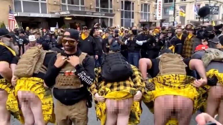 Proud Boys in kilts at a protest bend over to show what clever things they have written on their buttocks. 