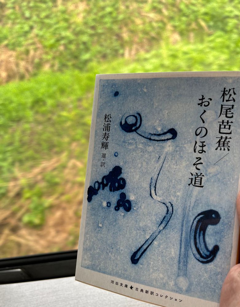 電車の車窓から見える緑と本の写真　
河出文庫　松尾芭蕉/おくのほそ道　松浦寿輝選　訳