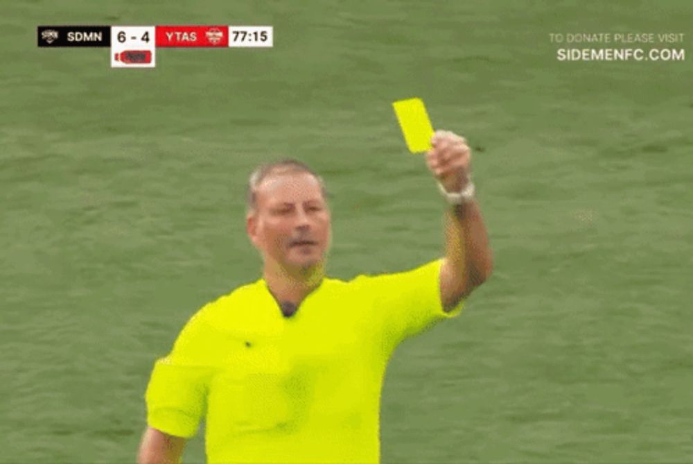 a referee giving a yellow card to a player in a red shirt