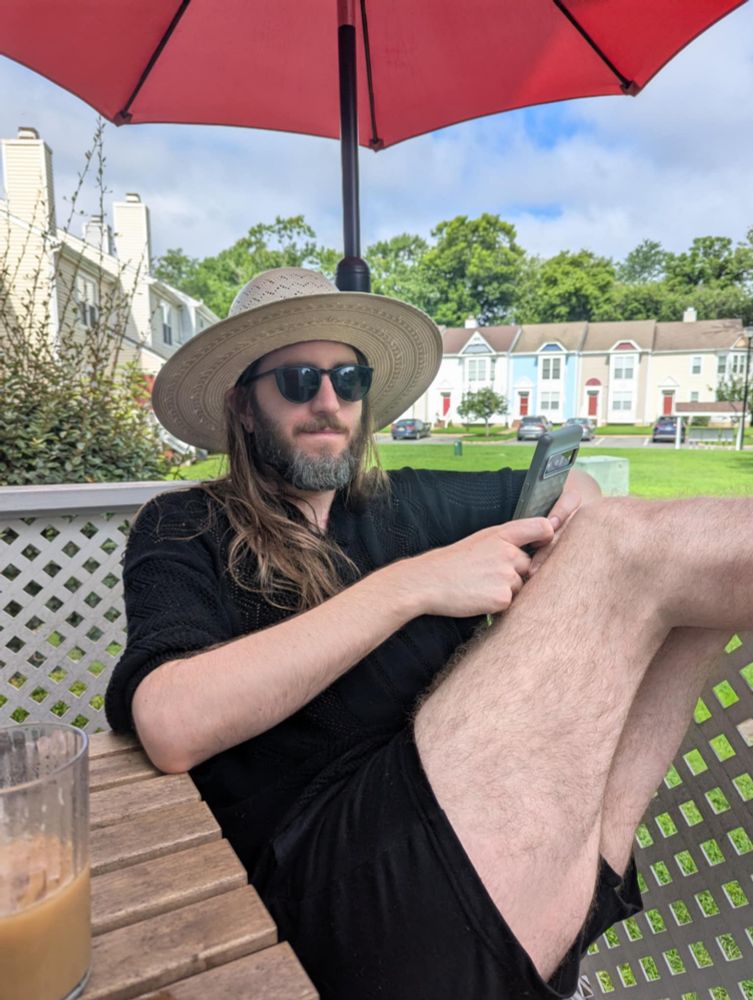 Me in all black wearing a brimmed hat with my legs up