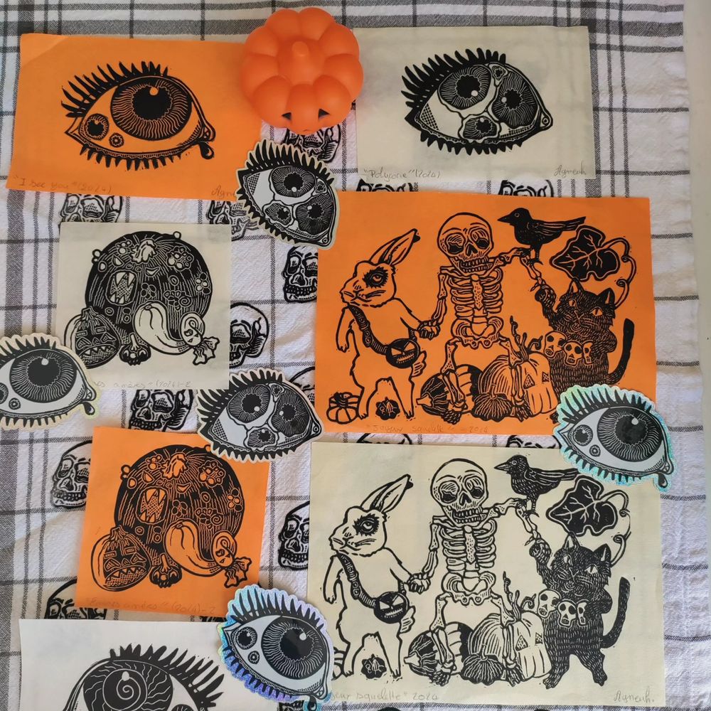 Impressions.linogravure spécial Halloween. Sur papier orange et ivoire. Impression citrouilles air menaçante, sur papier carré. Squelette entouré d'un chat et d'un lapin dans un champ de citrouilles. Impression œil et stickers pailletés