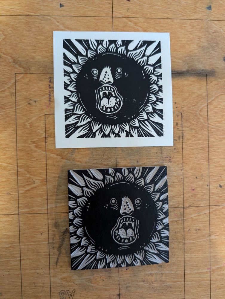 Linocut representing a sun exploding, mouth wide Open. I'm a square. The block is under the print 
