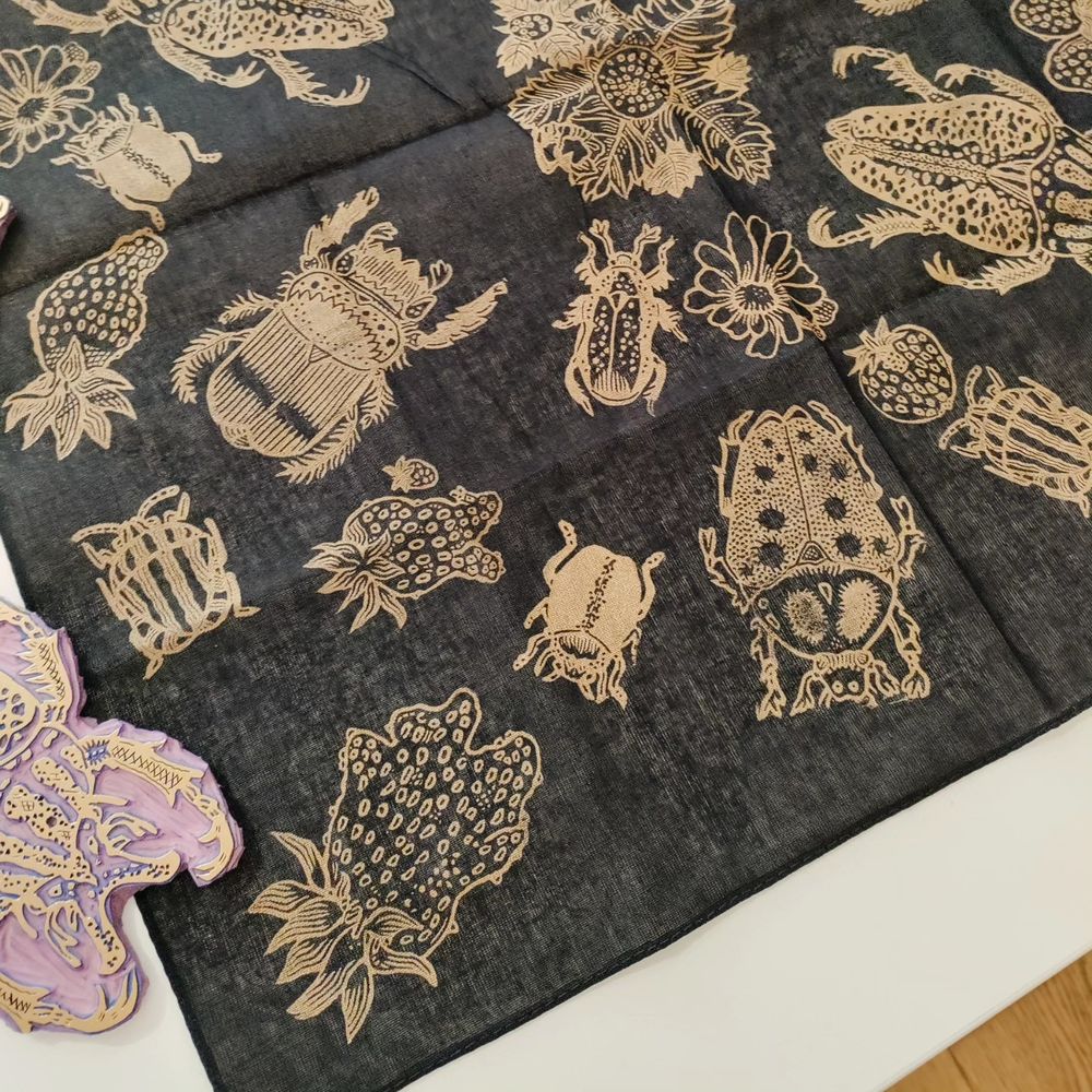 Foulard noir imprimé en dorée, motifs scarabées et fraises.
