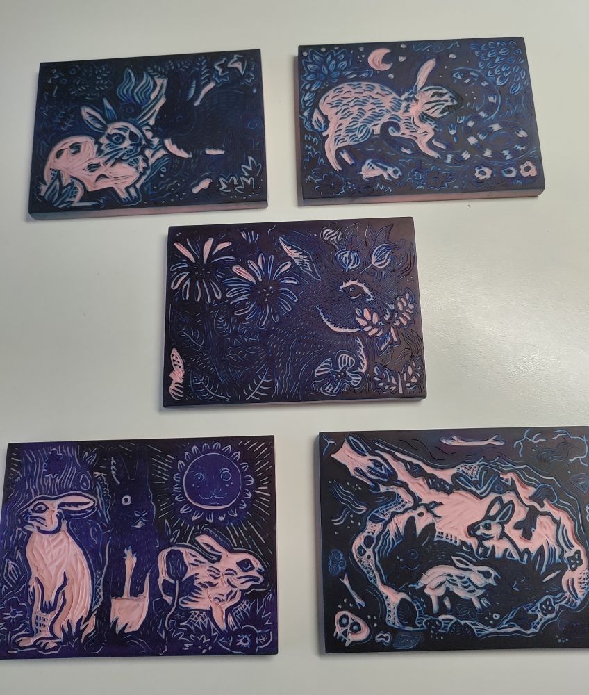Cinq plaques linogravure/gomme rose, gravées avec différentes scènes avec des lapins.