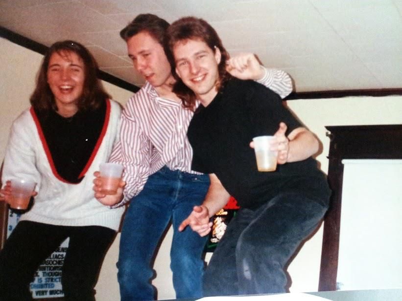 2 men and 1 woman in 1991 dancing on a bar at a college party while holding plastic beer cups. 