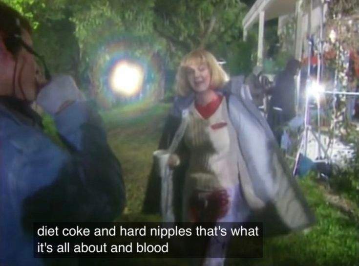 Still from behind the scenes of Scream (1996) of Drew Barrymore in her scene costume and fake blood, saying, "Diet Coke and hard nipples — that's what it's all about. And blood."