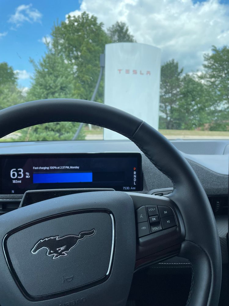 View from driver’s seat, showing a 63% charge on the dash and the v4 Supercharger through the windshield. 