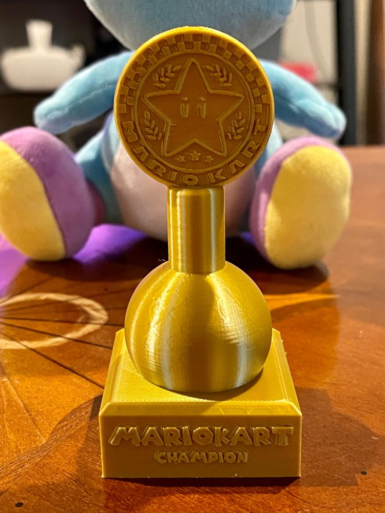 A close up of the Mario Kart trophy. It has a Mario Star as the emblem and it says “MARIOKART CHAMPION” at the base of the trophy.