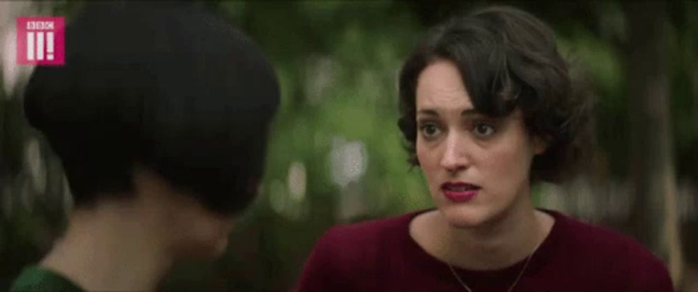 a woman covering her ears with her hand while another woman looks at her .