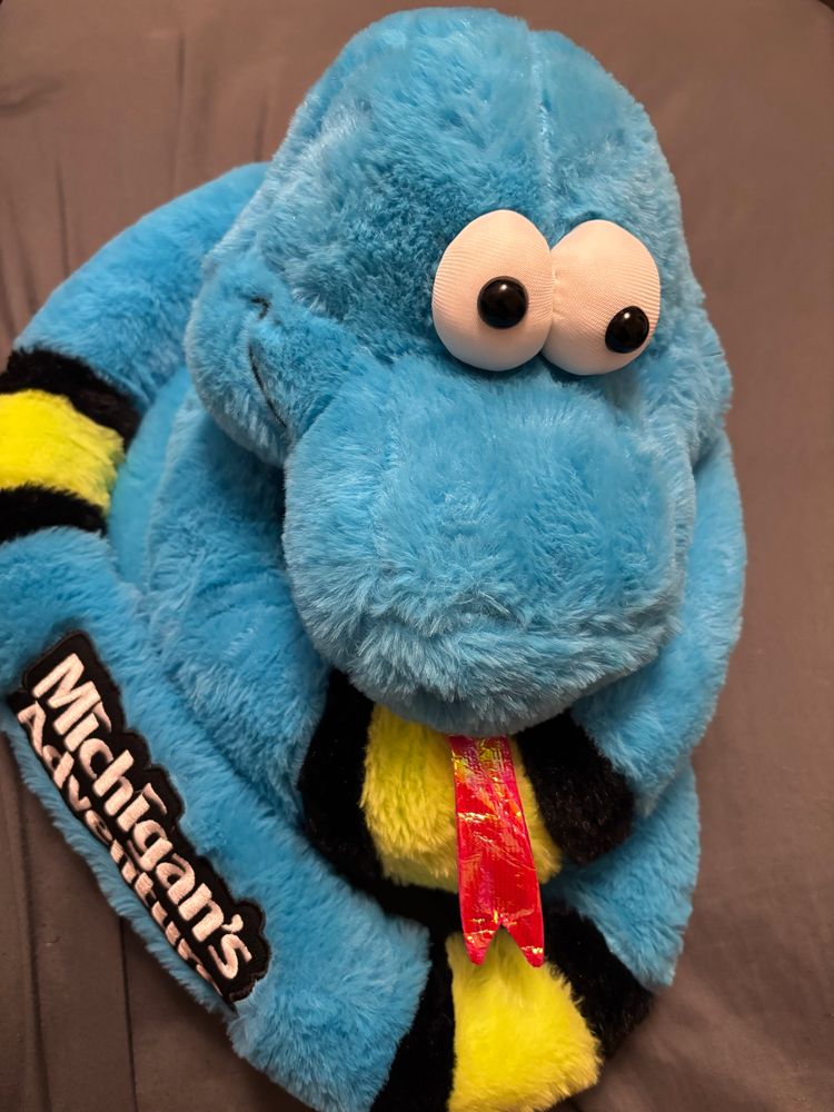 A large blue snake plushie wrapped in a coil with his red tongue out. On the outer coil it says “Michigan’s Adventure”. 