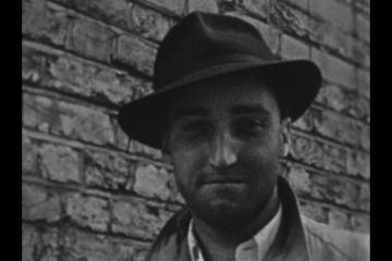 Actor John Anderson wearing a hat, smiling slightly into the camera.