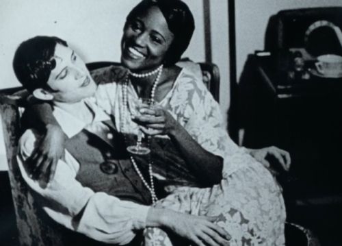 Photo by Zoe Leonard of Fae Richards smiling, sitting on the lap of Martha Page, who is looking at her. 