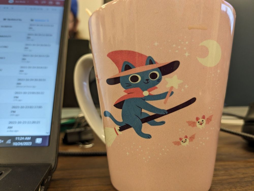 image of a mug with a cartoon cat in a witch outfit riding a broom